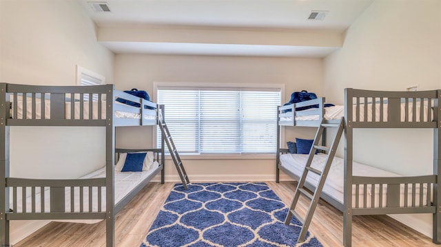 bedroom with baseboards, wood finished floors, and visible vents