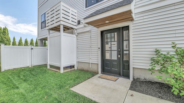 doorway to property featuring fence, a gate, and a lawn