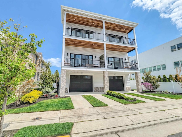 view of front of home featuring driveway, fence, a balcony, an attached garage, and stone siding