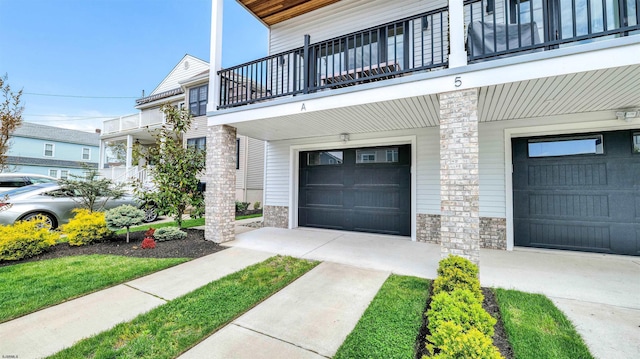 exterior space featuring a balcony, stone siding, and a garage