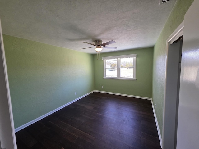 unfurnished room with a textured ceiling, ceiling fan, baseboards, and dark wood-type flooring