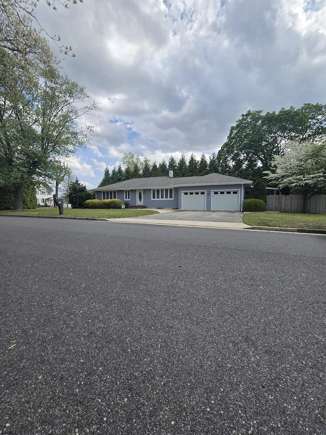 manufactured / mobile home with fence, a chimney, driveway, and a garage