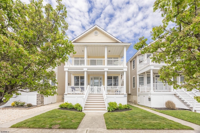 greek revival house with a porch, a front lawn, stairs, and a balcony