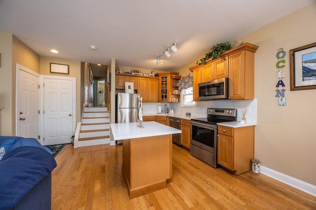 kitchen with light countertops, stainless steel appliances, brown cabinets, and light wood-style flooring