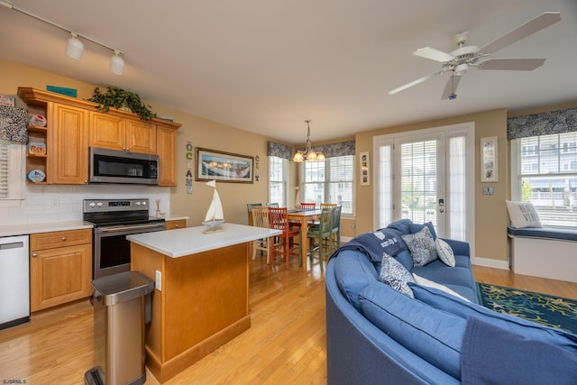 kitchen featuring light countertops, stainless steel appliances, open floor plan, and track lighting