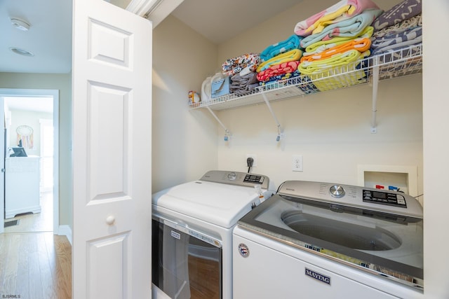 washroom with separate washer and dryer, laundry area, and wood finished floors