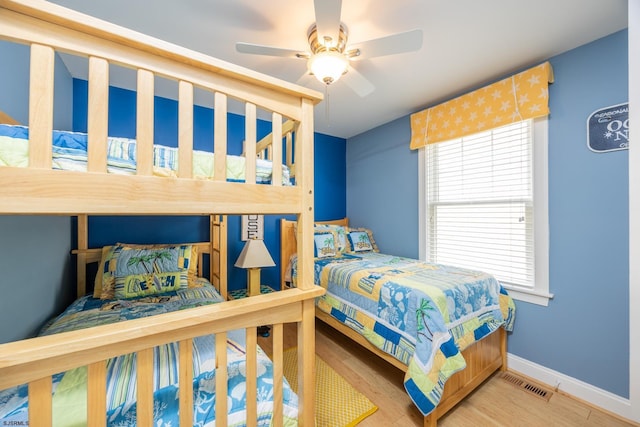 bedroom with visible vents, a ceiling fan, baseboards, and wood finished floors
