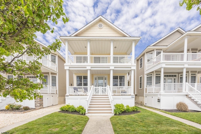 view of front facade featuring stairs, a balcony, covered porch, and a front yard