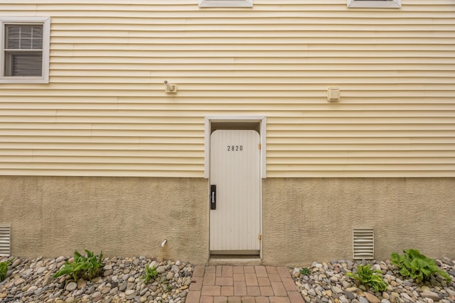 doorway to property featuring visible vents and stucco siding