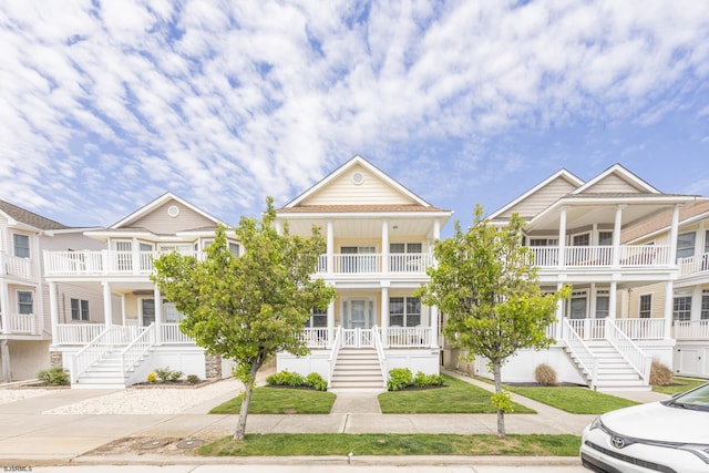 view of property with stairs, a porch, and a balcony