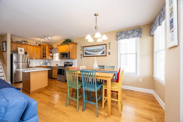 dining room with light wood-style floors, baseboards, visible vents, and an inviting chandelier