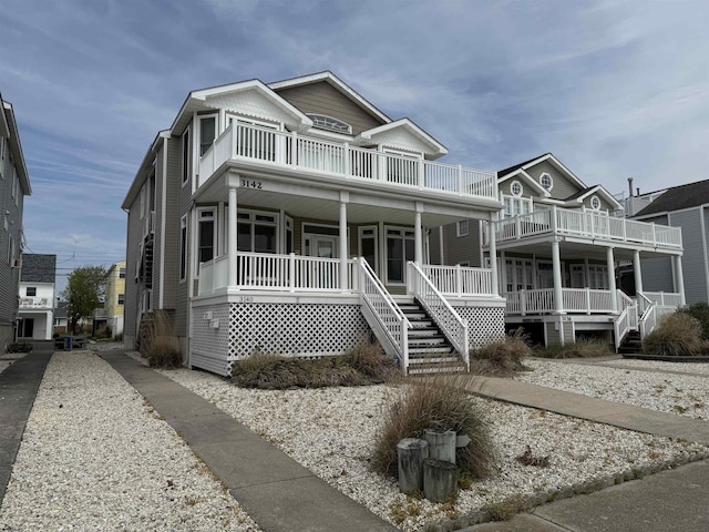 view of front of house with stairs, a porch, and a balcony