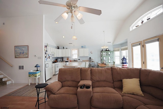 living area with light tile patterned flooring, high vaulted ceiling, visible vents, and a ceiling fan