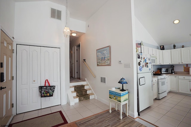 interior space with high vaulted ceiling, stairs, light tile patterned flooring, and visible vents