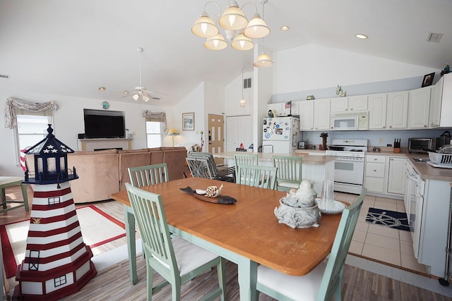 dining room with visible vents, ceiling fan with notable chandelier, a toaster, and high vaulted ceiling