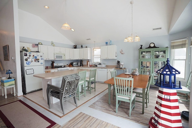 dining space with light tile patterned floors, high vaulted ceiling, visible vents, and an inviting chandelier
