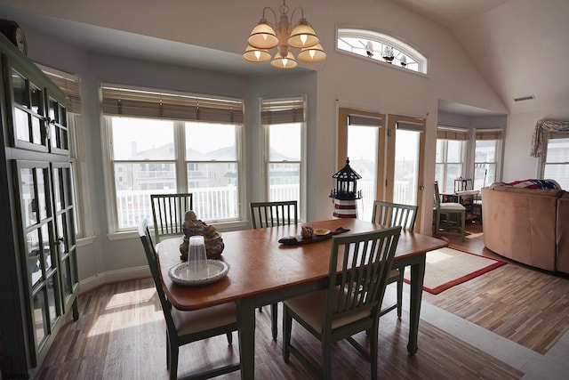 dining area with visible vents, lofted ceiling, wood finished floors, and a notable chandelier