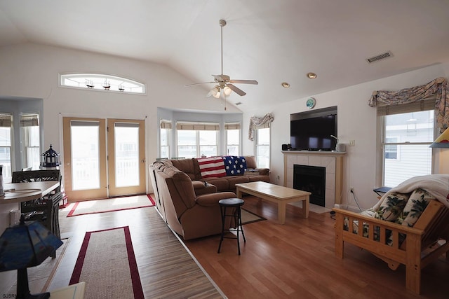 living area featuring a ceiling fan, vaulted ceiling, light wood-style flooring, and visible vents