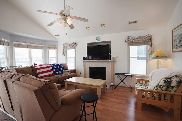 living area featuring vaulted ceiling, a healthy amount of sunlight, visible vents, and a tile fireplace