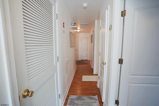 corridor featuring baseboards and wood finished floors