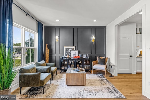 sitting room with recessed lighting, light wood-style flooring, and a decorative wall