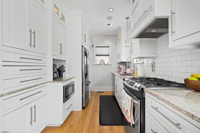 kitchen with white cabinets, light wood-style floors, appliances with stainless steel finishes, and a sink