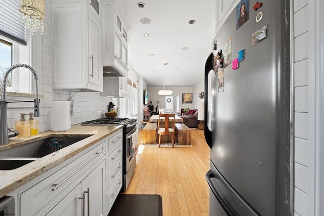 kitchen with glass insert cabinets, a sink, white cabinetry, backsplash, and appliances with stainless steel finishes
