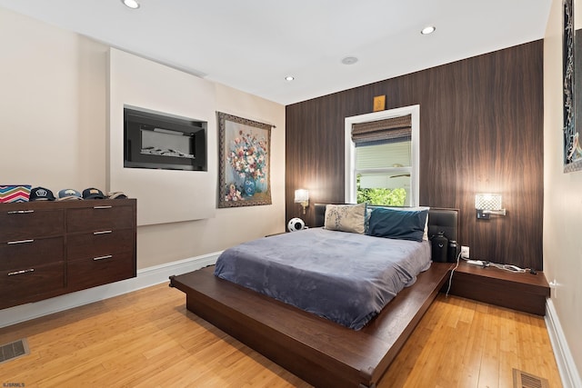 bedroom with wood finished floors, visible vents, and baseboards