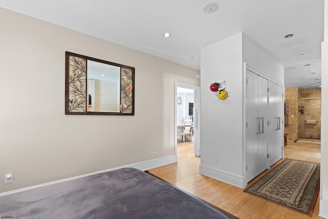 interior space featuring connected bathroom, light wood-style flooring, a closet, baseboards, and recessed lighting