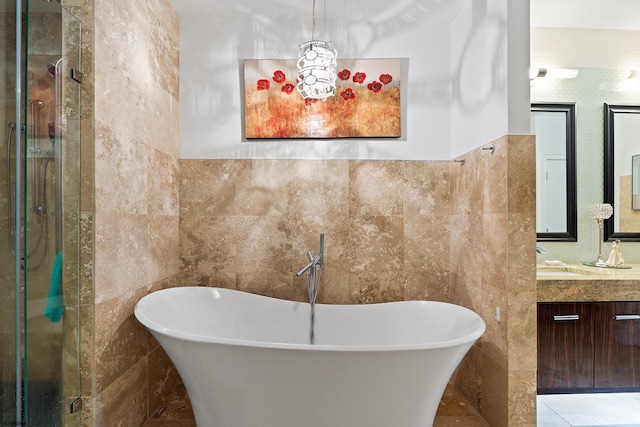 full bathroom with tile walls, vanity, and a freestanding tub