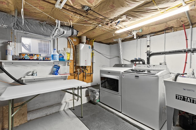 washroom featuring washing machine and dryer, water heater, a sink, and laundry area