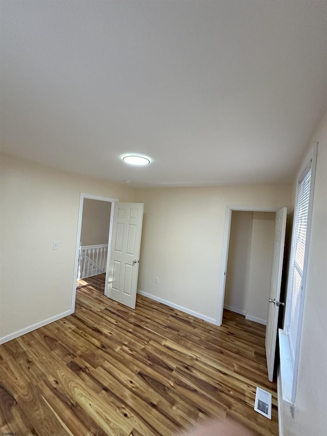 unfurnished room featuring visible vents, wood finished floors, and baseboards