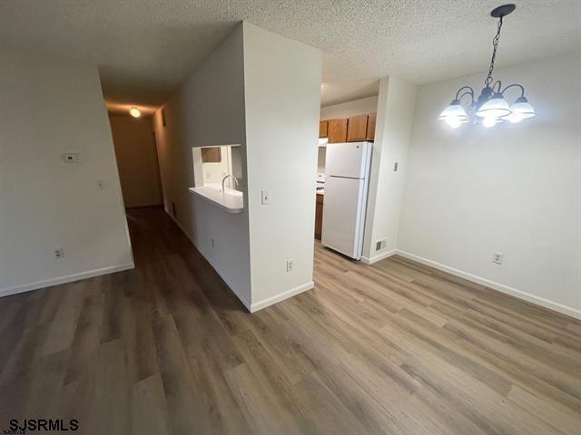 66 Sussex Ln Unit 66, Galloway Township, NJ 08205 - empty room featuring an inviting chandelier, a textured ceiling, baseboards, and wood finished floors