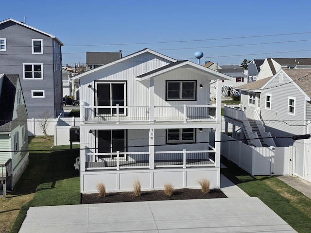 rear view of house with a balcony, a yard, and fence