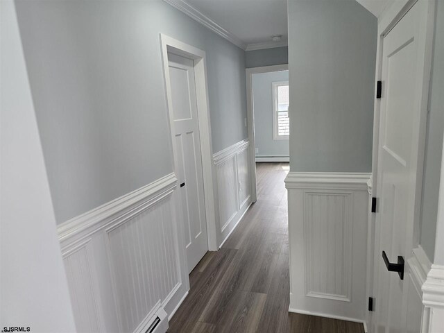 hallway featuring a baseboard radiator, ornamental molding, dark wood finished floors, wainscoting, and a decorative wall