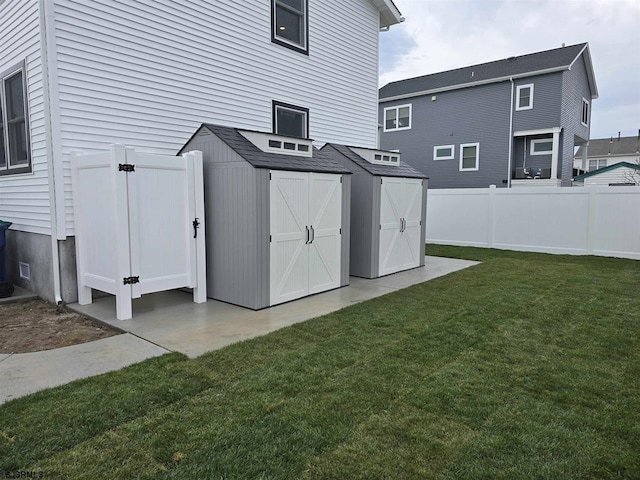 rear view of house with a storage shed, a yard, an outdoor structure, and fence