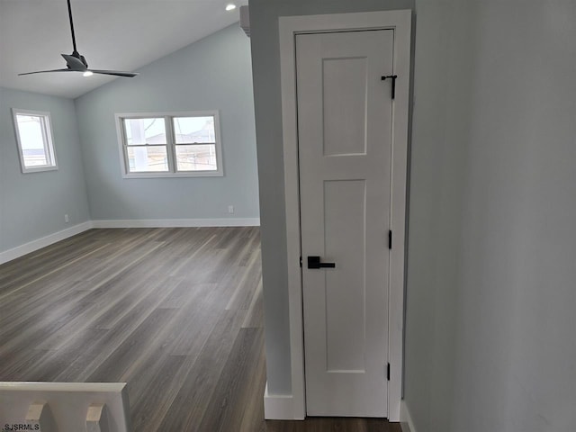 unfurnished room featuring vaulted ceiling, dark wood-style flooring, baseboards, and a ceiling fan