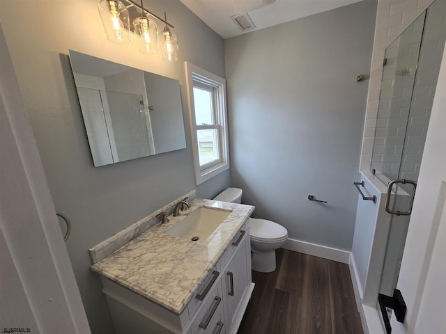 bathroom with toilet, visible vents, a shower stall, vanity, and wood finished floors