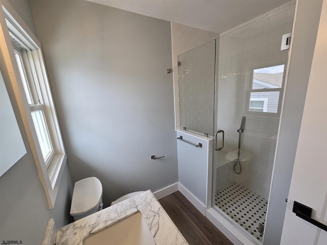 full bath with toilet, wood finished floors, a stall shower, a sink, and baseboards