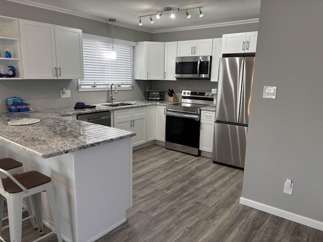 kitchen featuring a peninsula, a sink, stainless steel appliances, white cabinets, and light stone counters