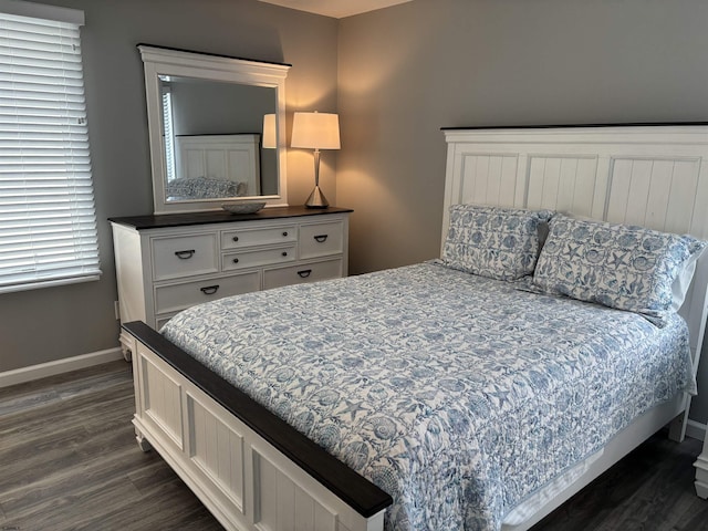 bedroom with dark wood finished floors and baseboards