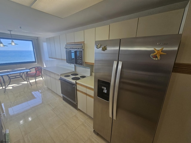 kitchen with stainless steel fridge, white electric range, black microwave, light countertops, and light tile patterned floors