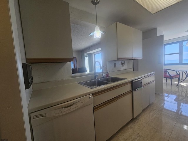 kitchen featuring white dishwasher, a sink, healthy amount of natural light, and light countertops