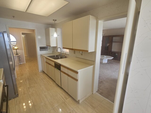 kitchen with a sink, freestanding refrigerator, light countertops, hanging light fixtures, and dishwashing machine