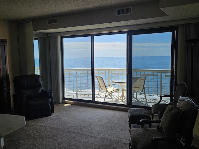 carpeted living area featuring a water view and a textured ceiling