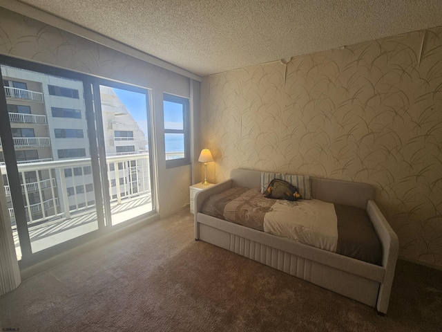 bedroom with a textured ceiling, wallpapered walls, carpet flooring, and access to outside
