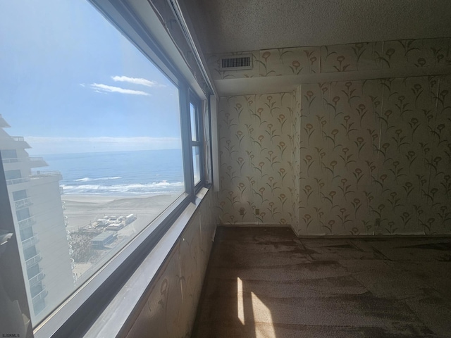 unfurnished room with a water view and a textured ceiling