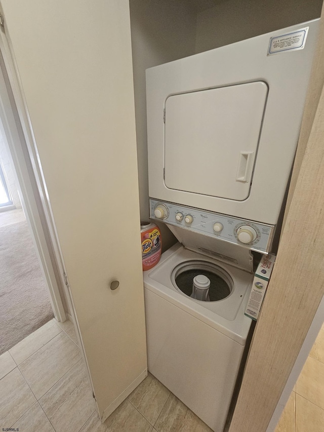 laundry area featuring stacked washer / dryer and light tile patterned flooring