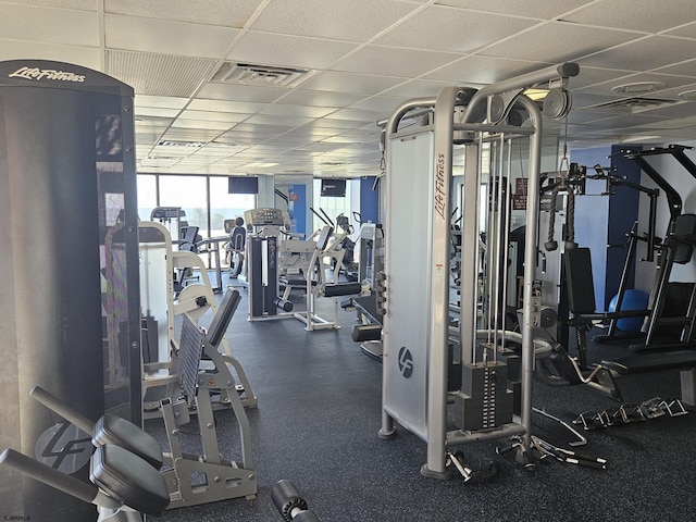 workout area with a paneled ceiling and a wall of windows