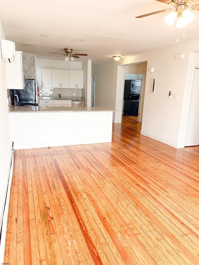 kitchen with a ceiling fan, light wood finished floors, decorative backsplash, and baseboard heating